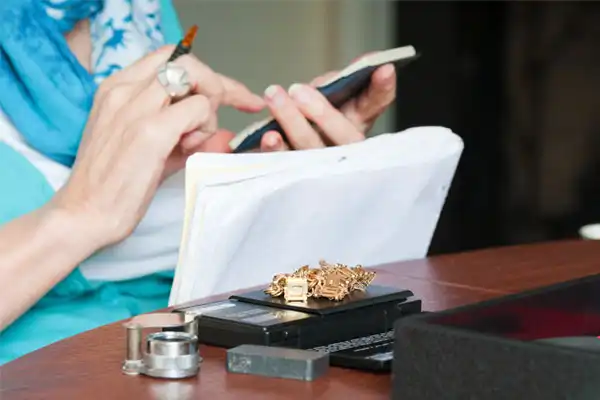 An appraiser measures the weight of gold items.